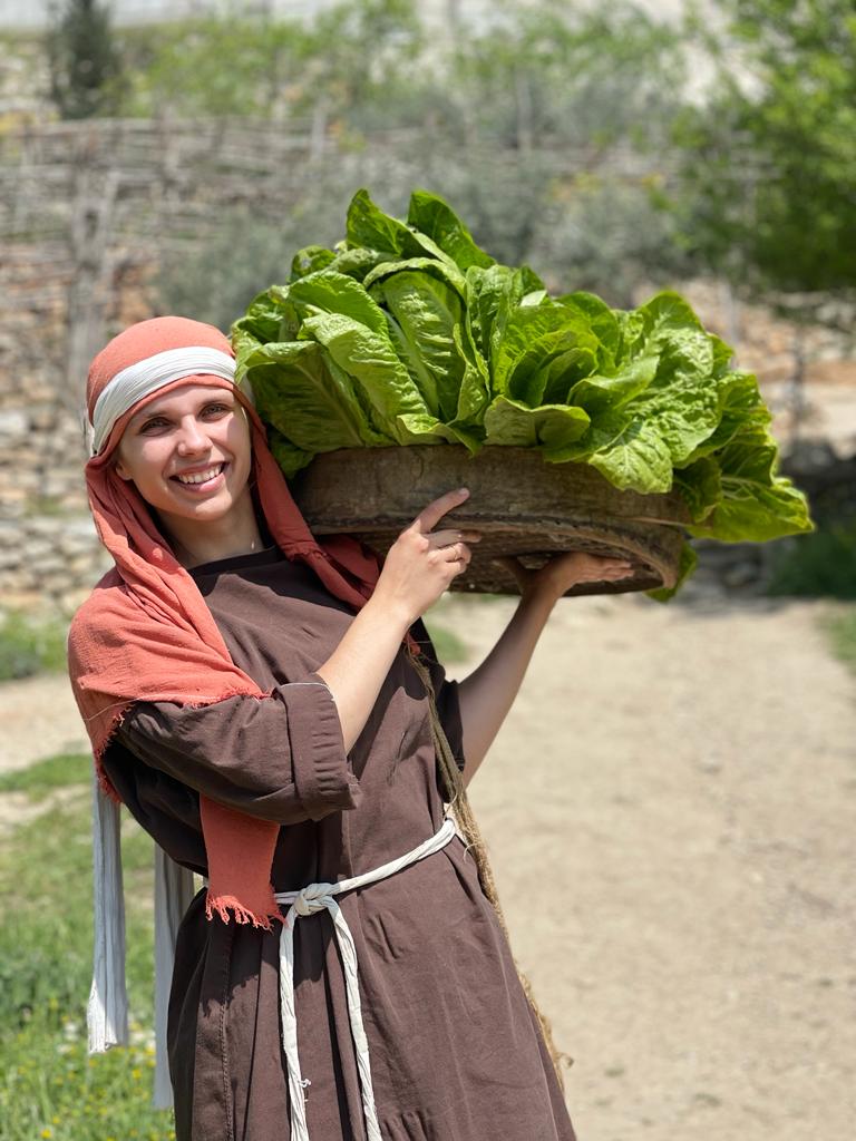 Monika working at the Nazareth Village, holding a basket of lettuce.